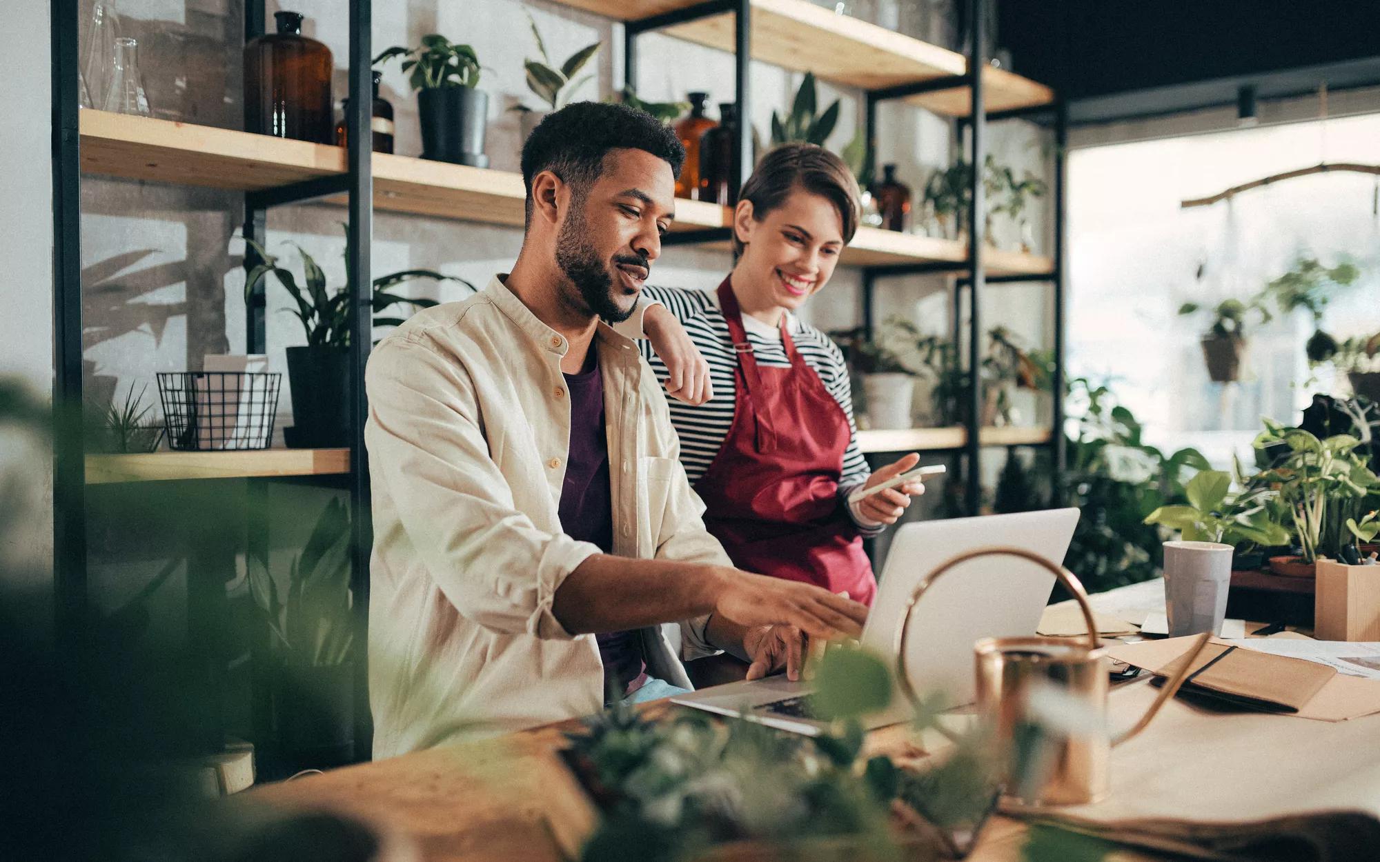 Two people looking at a laptop working together in a plant shop.