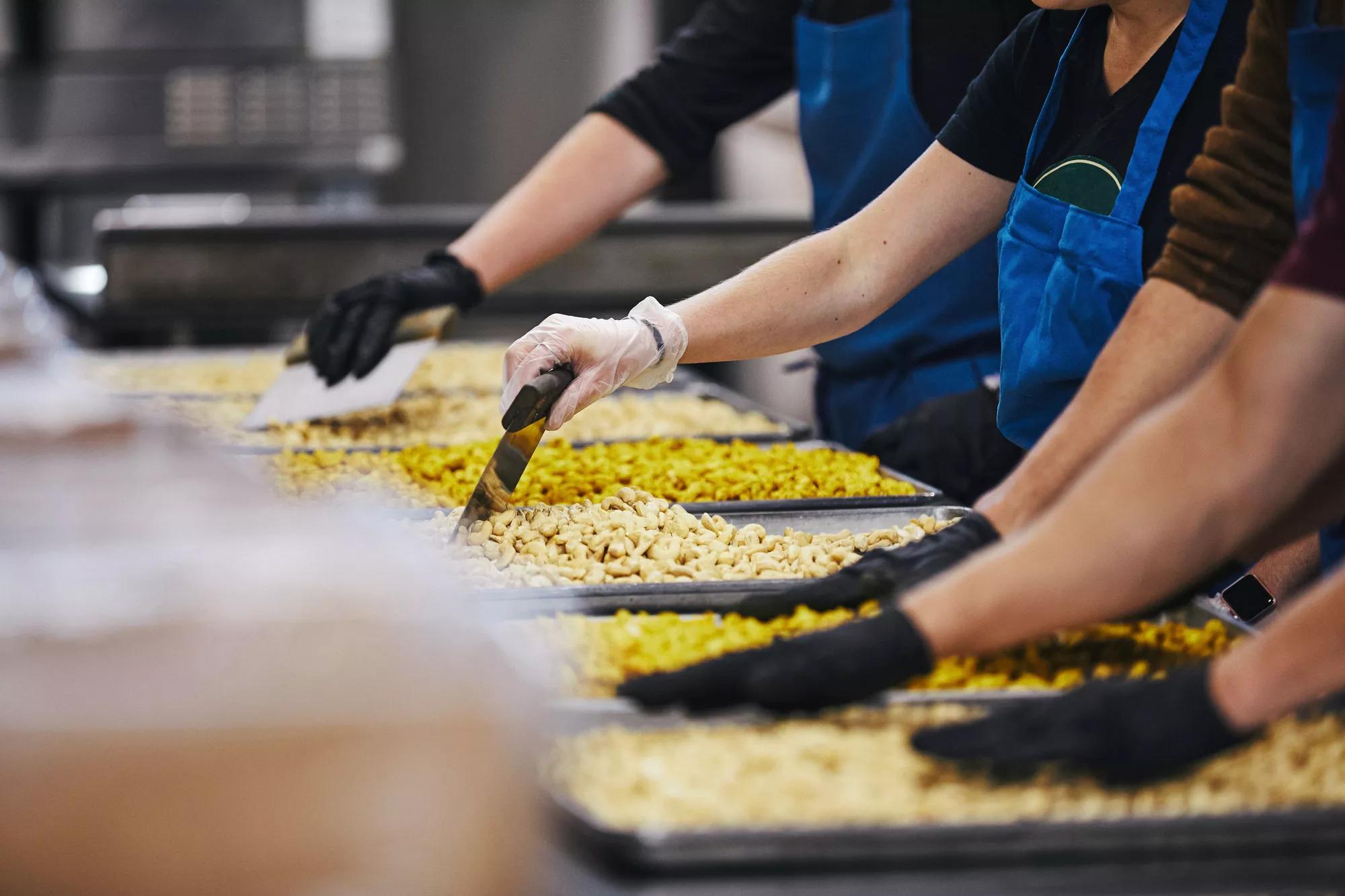 Three workers in a kitchen, prepping to serve food to people in need.