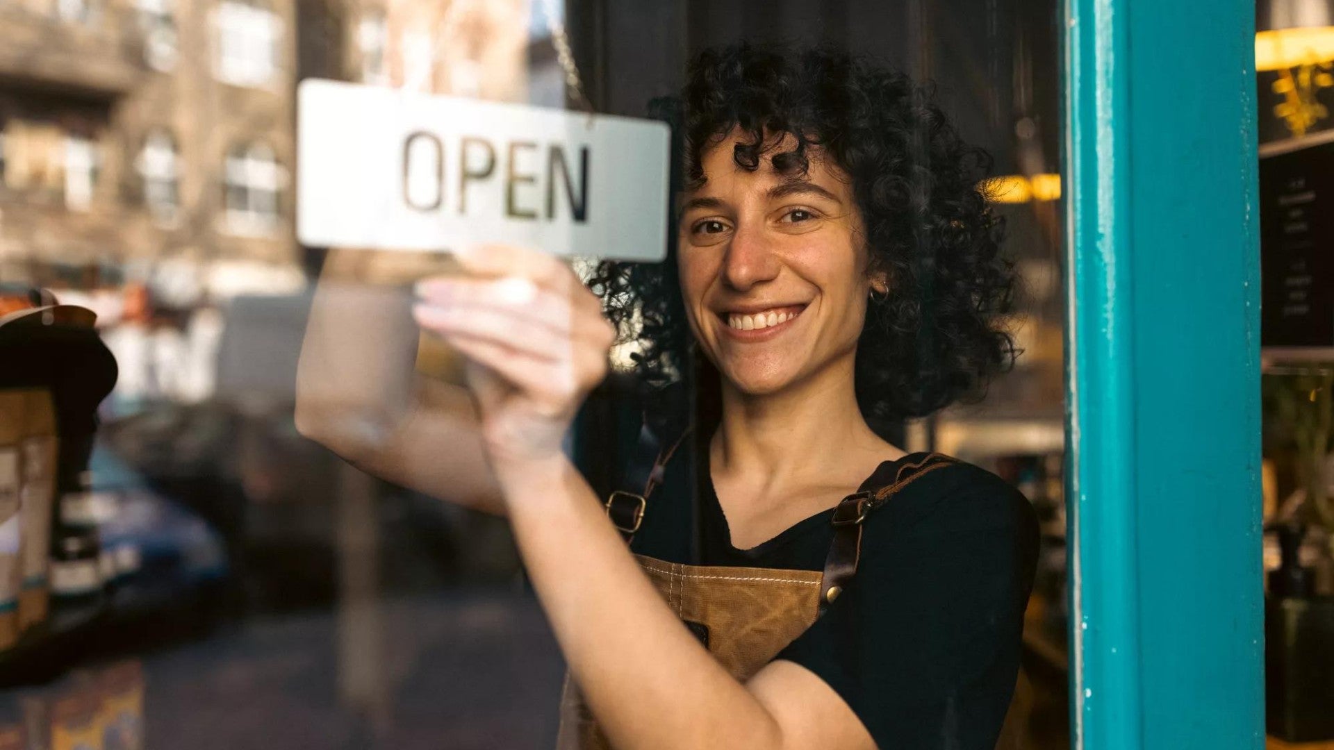 Woman smiling opening her storefront.