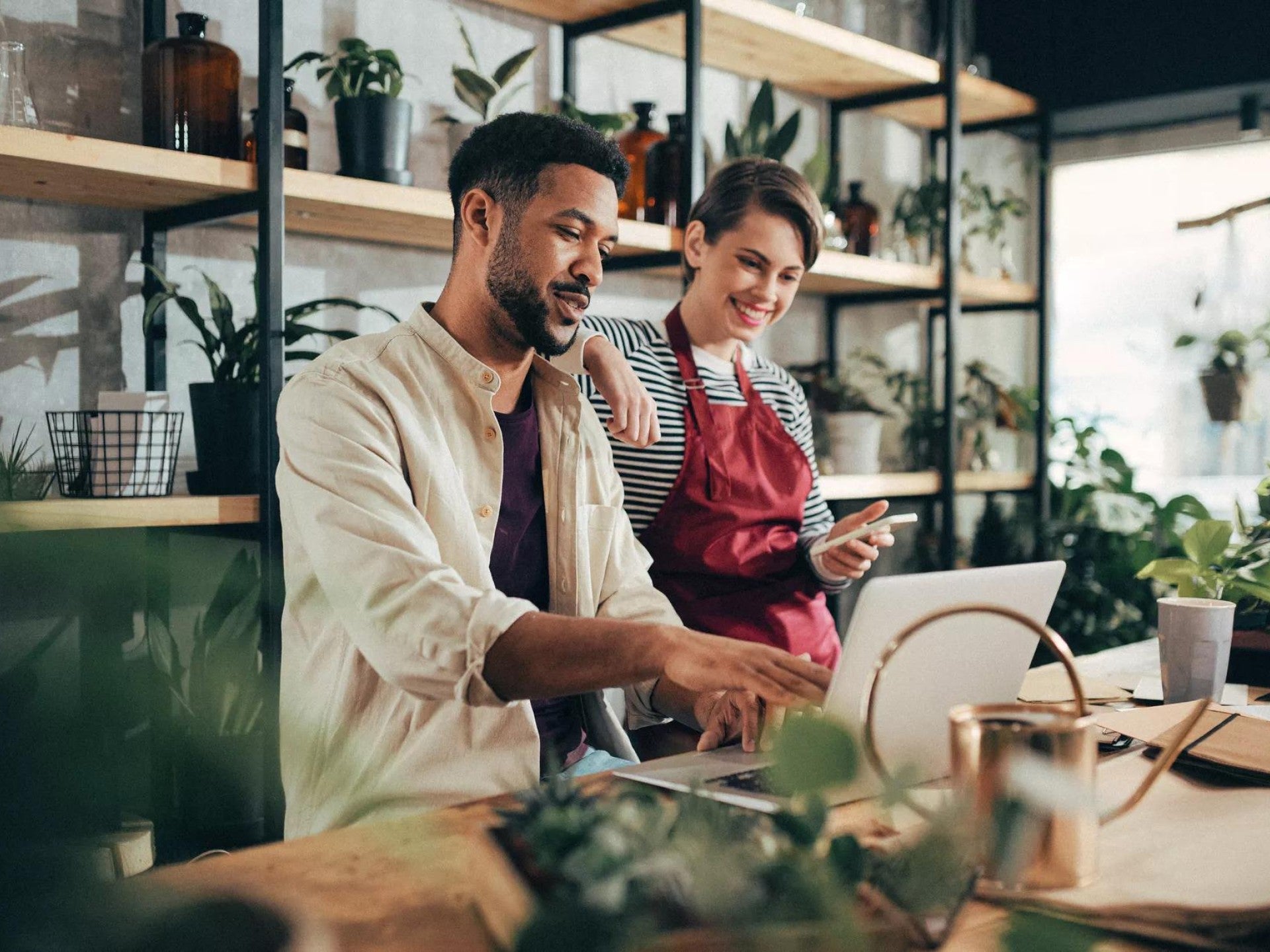 Two people looking at a laptop working together in a plant shop.