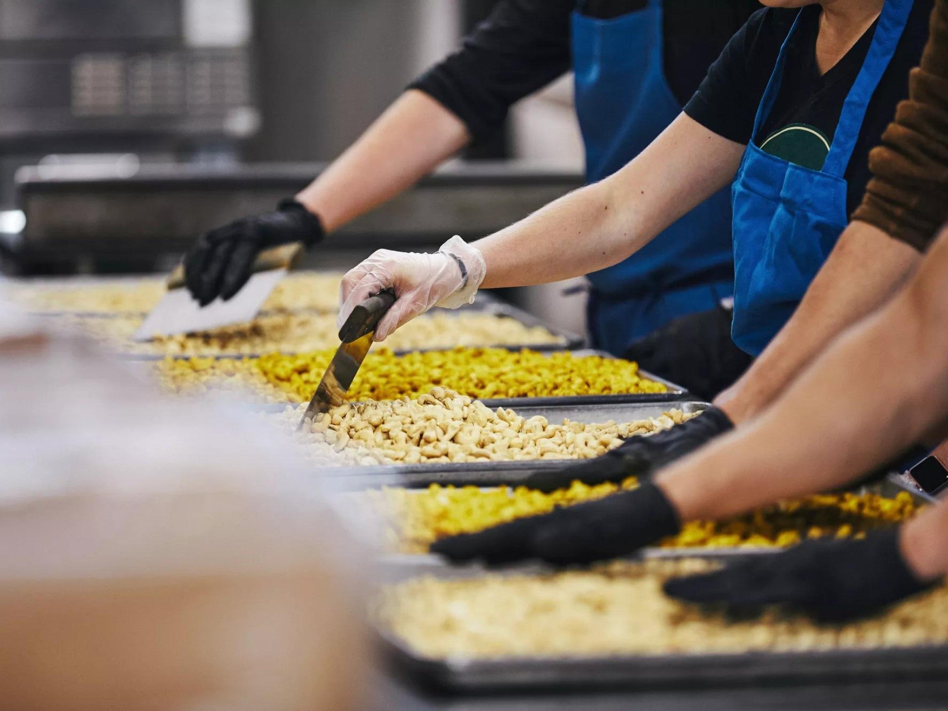 Three workers in a kitchen, prepping to serve food to people in need.