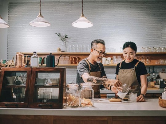 Fostering social and cultural connections Two people working together in a coffee shop.